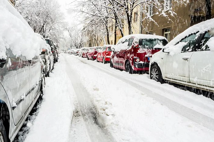 Schneereiche Straße mit parkenden Autos